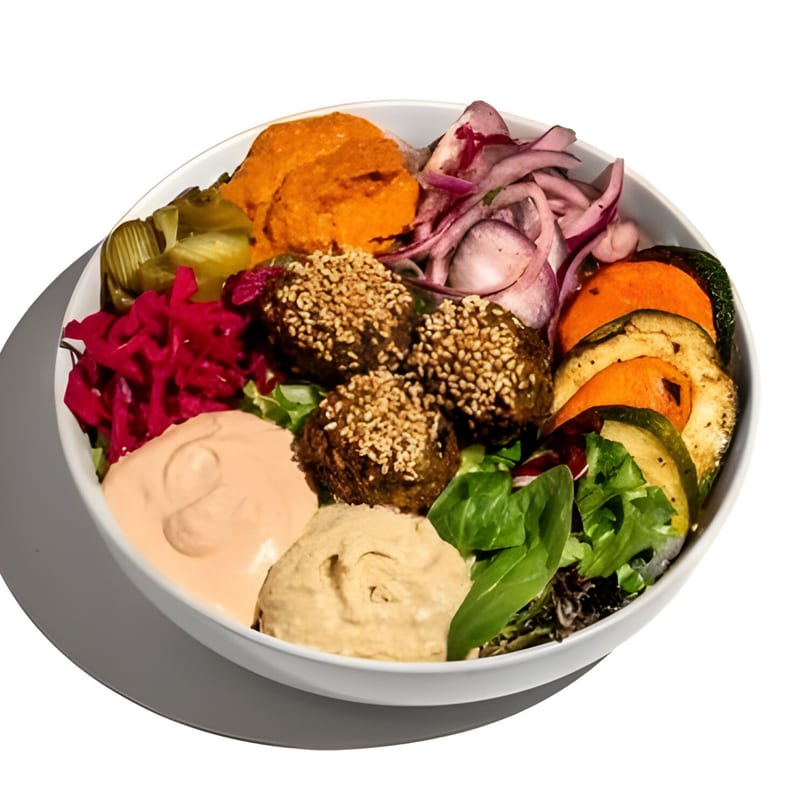 A vibrant Mediterranean bowl with falafel, hummus, roasted vegetables, pickled onions, and red cabbage.