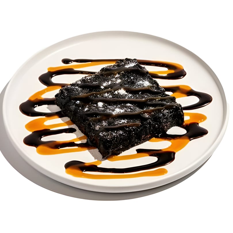Wild Pita's chocolate brownie with powdered sugar, chocolate, and caramel drizzle on a white plate.